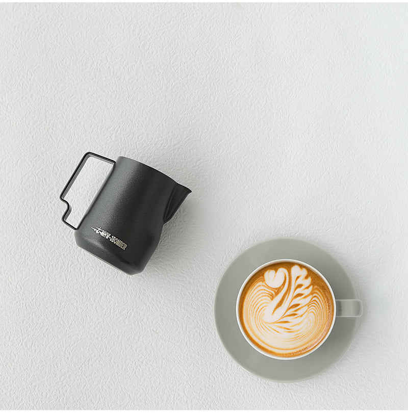 Pichet à lait MHW-3BOMBER Turbo en noir mat (Matte Black) avec un cappuccino et du latte art, vue de dessus