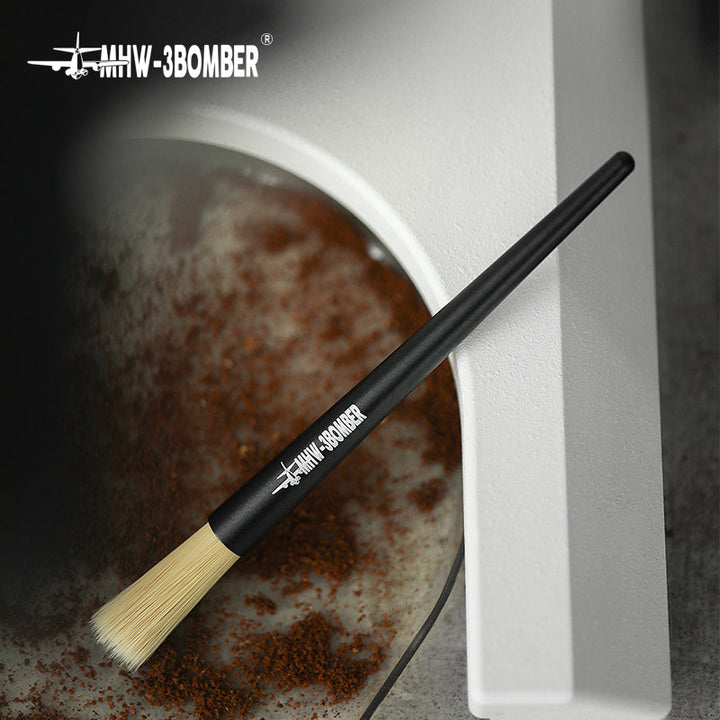 Pinceau barista MHW-3BOMBER Pen Brush en noir mat (Matte Black) dans la sortie d’un moulin à café