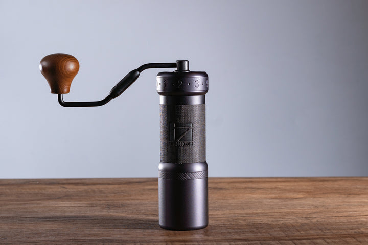 1Zpresso K-Ultra Eisengrau mit Kurbel, stehend auf Holztisch – Coffee Coaching Club 13
