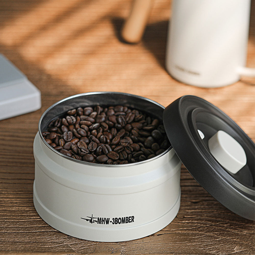 Boîte sous vide MHW-3BOMBER 750 ml en blanc avec intérieur en inox, remplie de grains de café