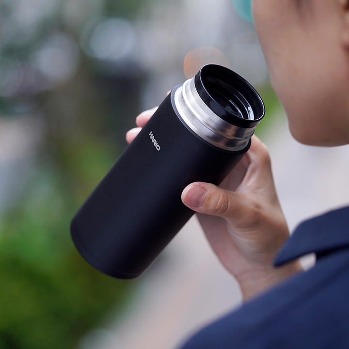 Hario Stick Bottle 350 ml en noir (Black) bue en déplacement, bouchon dévissé