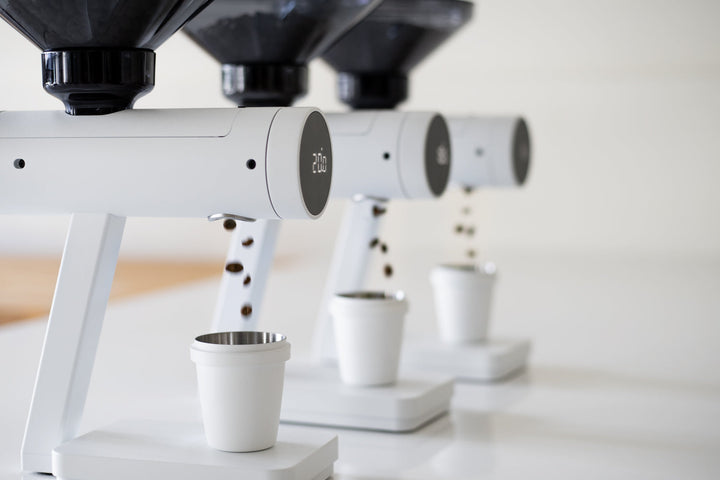 Acaia Orion Mini Mattweiss dosiert Bohnen in Becher, drei Geräte nebeneinander – Coffee Coaching Club 8
