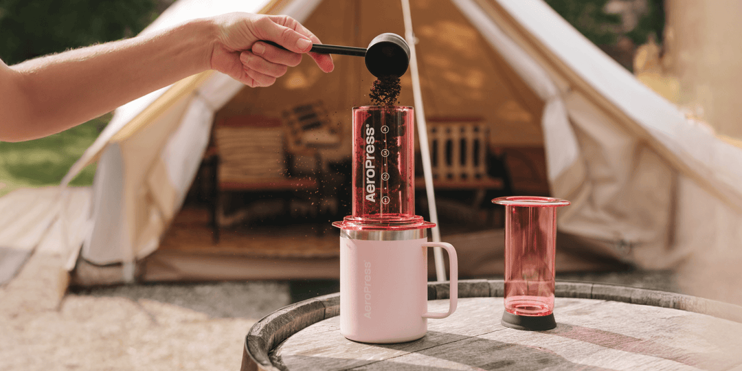 Farbige AeroPress Clear wird vor einem Zelt mit Kaffee befüllt – Coffee Coaching Club 22