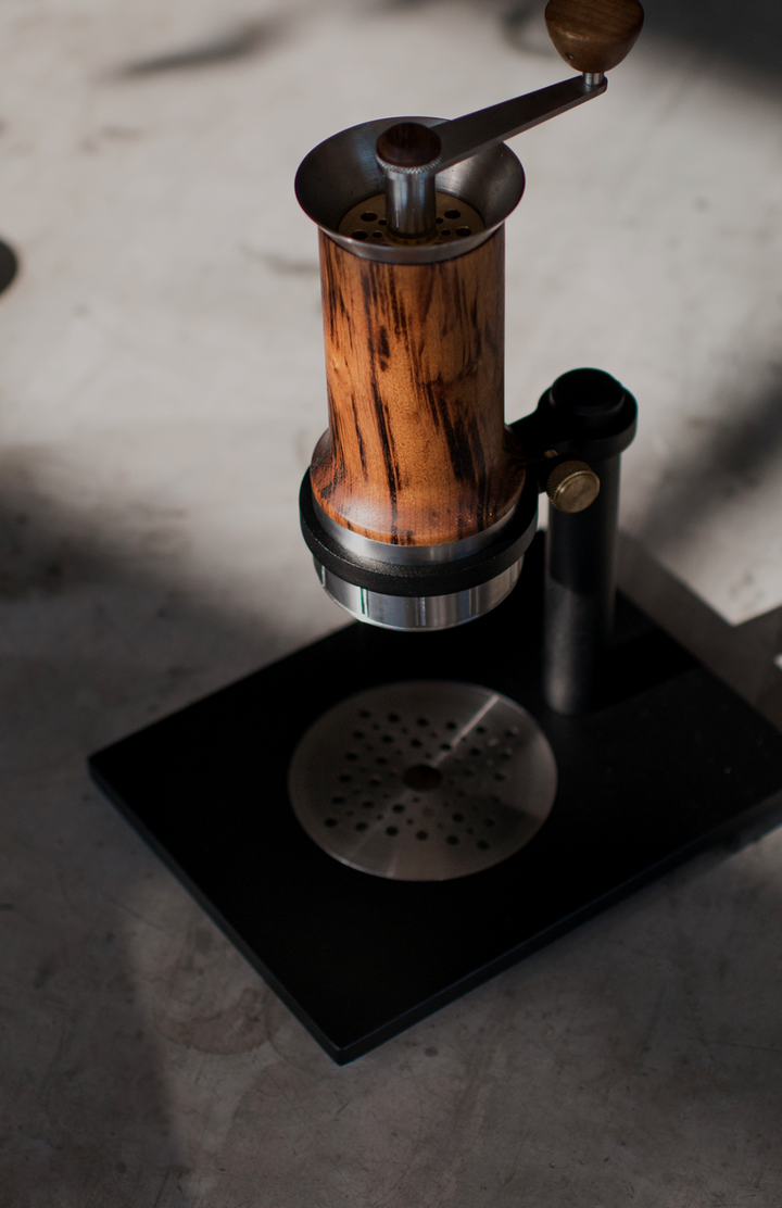Aram Espresso Maker aus Holz auf dem Stahlständer, Lifestyle auf grauer Fläche – Coffee Coaching Club 6
