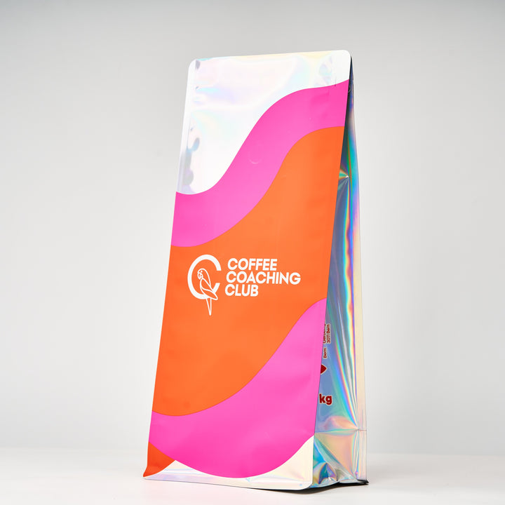 Caffè in grani Choco Rouge – sacchetto da 1 kg visto di lato con soffietto olografico, design rosa e arancione – Coffee Coaching Club