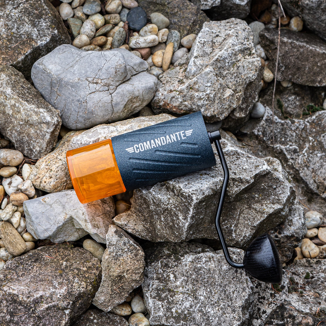 Comandante C60 Baracuda Nautilus Blue liegend auf Steinen mit orangem Bohnenbehälter – Coffee Coaching Club 11