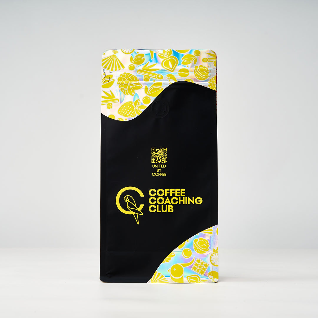 Miscela per espresso Cozy Nut – retro del sacchetto da 250 g con codice QR «United by Coffee», design nero e giallo – Coffee Coaching Club