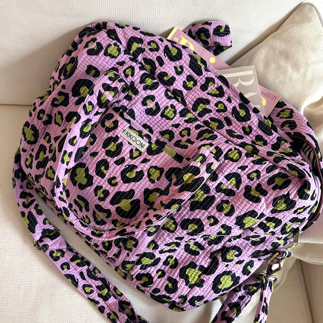 Kikooni Reisetasche Oh Leo Cosmic Lilac auf Sofa mit Zeitschrift – Coffee Coaching Club 2