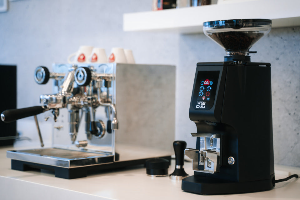 Eureka Atom W 65 Casa neben Espressomaschine auf der Theke – Coffee Coaching Club 8