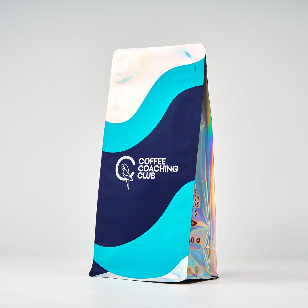 Caffè in grani Jungle Flower – sacchetto da 250 g visto di lato con soffietto olografico, design blu navy e turchese – Coffee Coaching Club