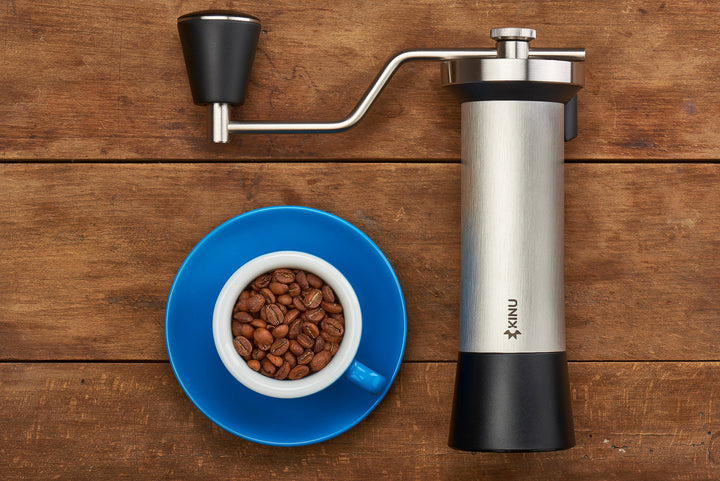 Kinu M47 Classic auf Holztisch neben Tasse mit Kaffeebohnen – Coffee Coaching Club 9