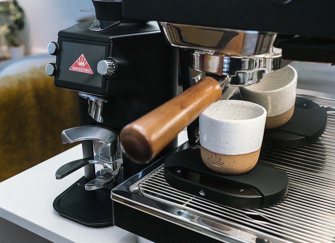Mahlkönig E64 WS Schwarz neben Espressomaschine mit Waage unter den Tassen – Coffee Coaching Club 10