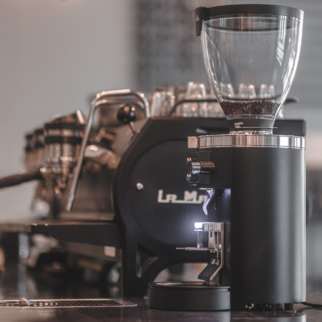 Mahlkönig E80S GbW Schwarz neben einer Espressomaschine im Café – Coffee Coaching Club 4