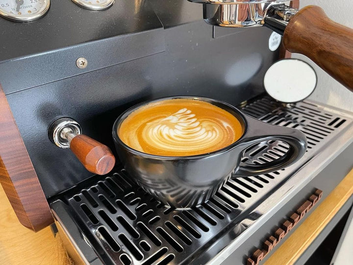 Normcore Espresso Shot Spiegel neben einer Tasse mit Latte Art auf dem Tropfgitter – Coffee Coaching Club 7