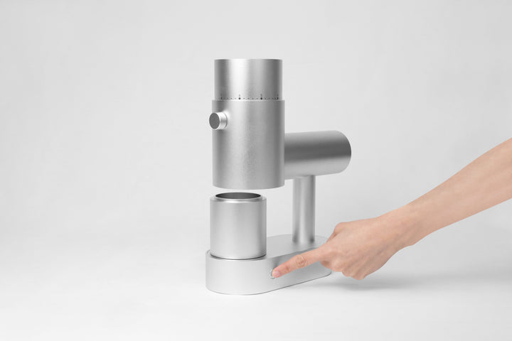 Option-O Lagom Casa Silber mit Mahlbecher auf dem Sockel, Hand an der Basis – Coffee Coaching Club 23