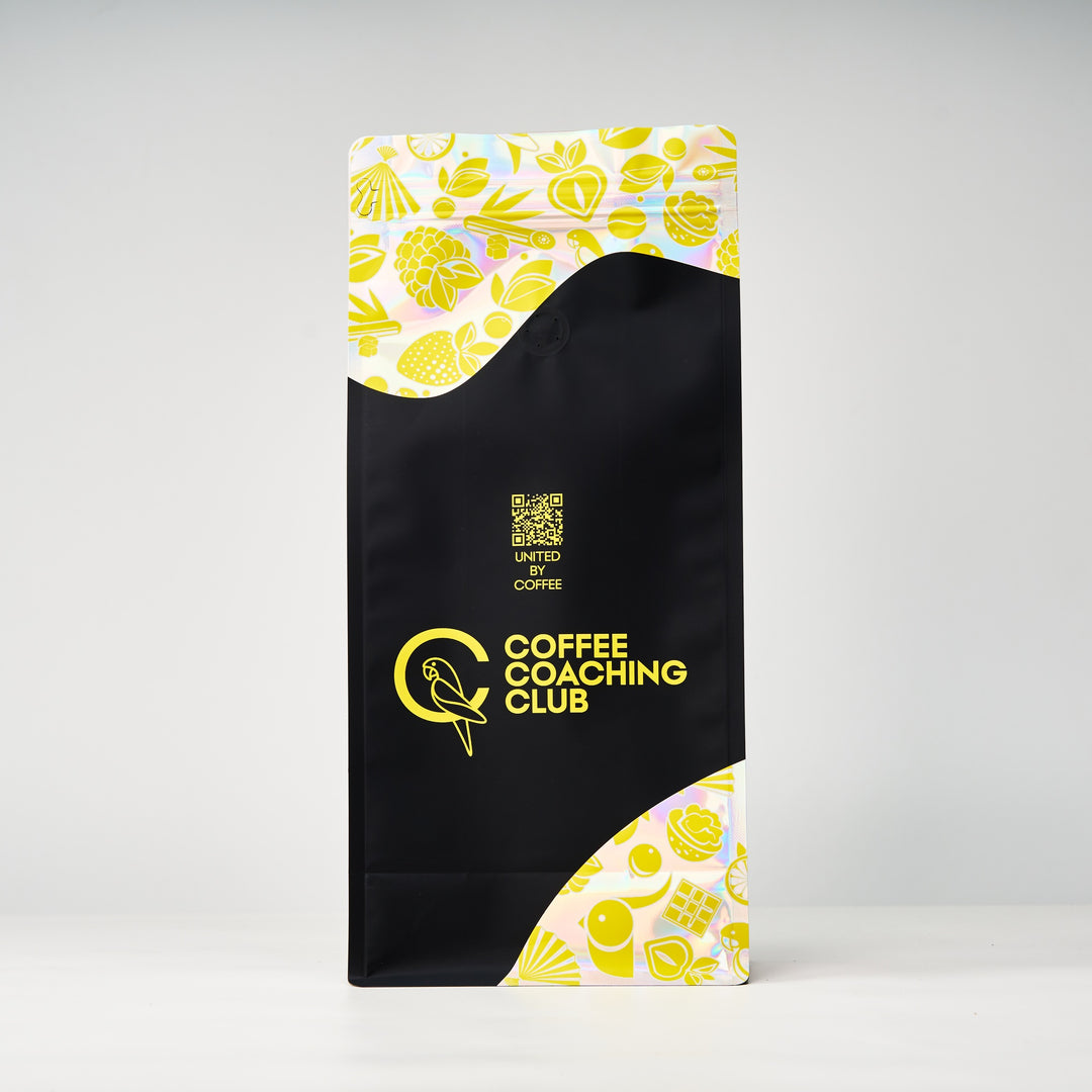 Caffè in grani Very Nutty – retro del sacchetto da 1 kg con codice QR «United by Coffee», design nero e giallo – Coffee Coaching Club