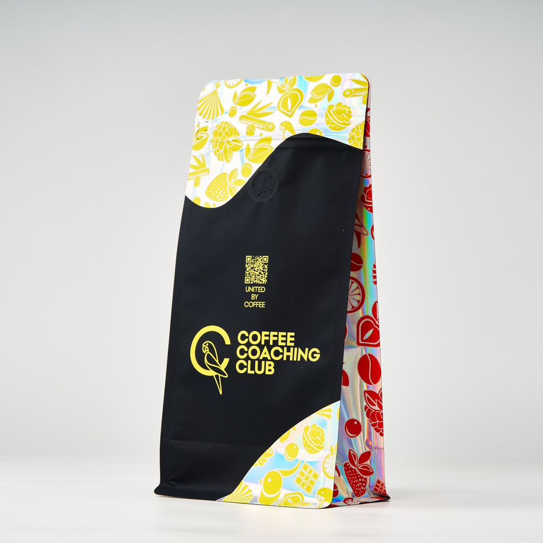 Caffè in grani Very Nutty – retro del sacchetto visto di sbieco con soffietto stampato, design nero e giallo – Coffee Coaching Club